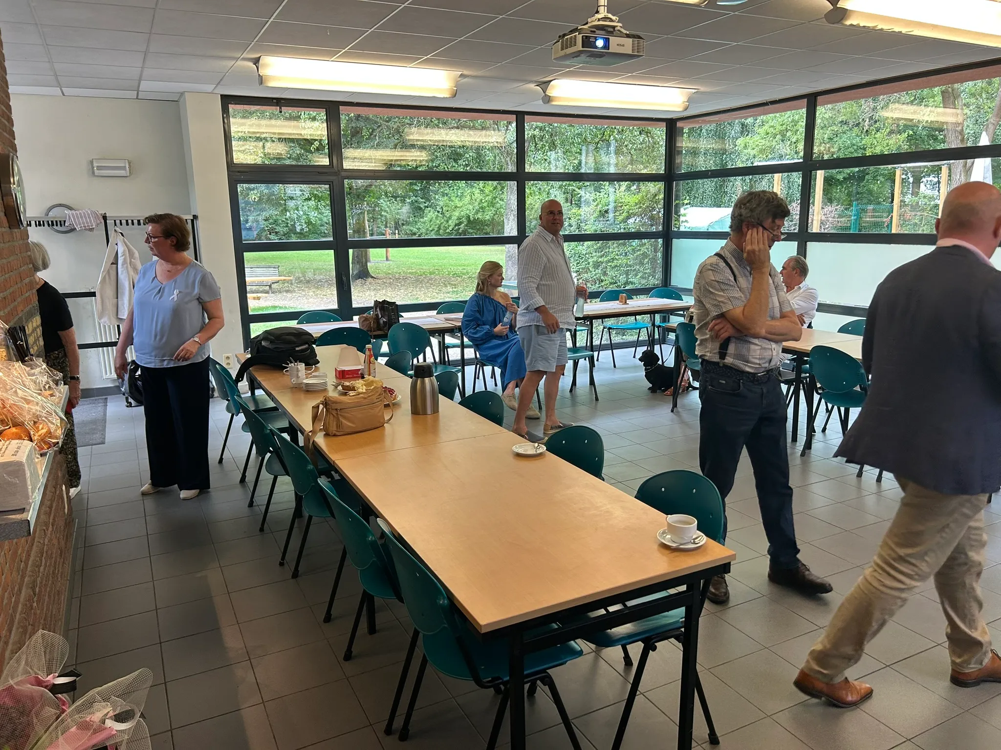 Deelnemers komen aan op een bijeenkomst van ALK Positive Belgium, in een lichte zaal met uitzicht op een park